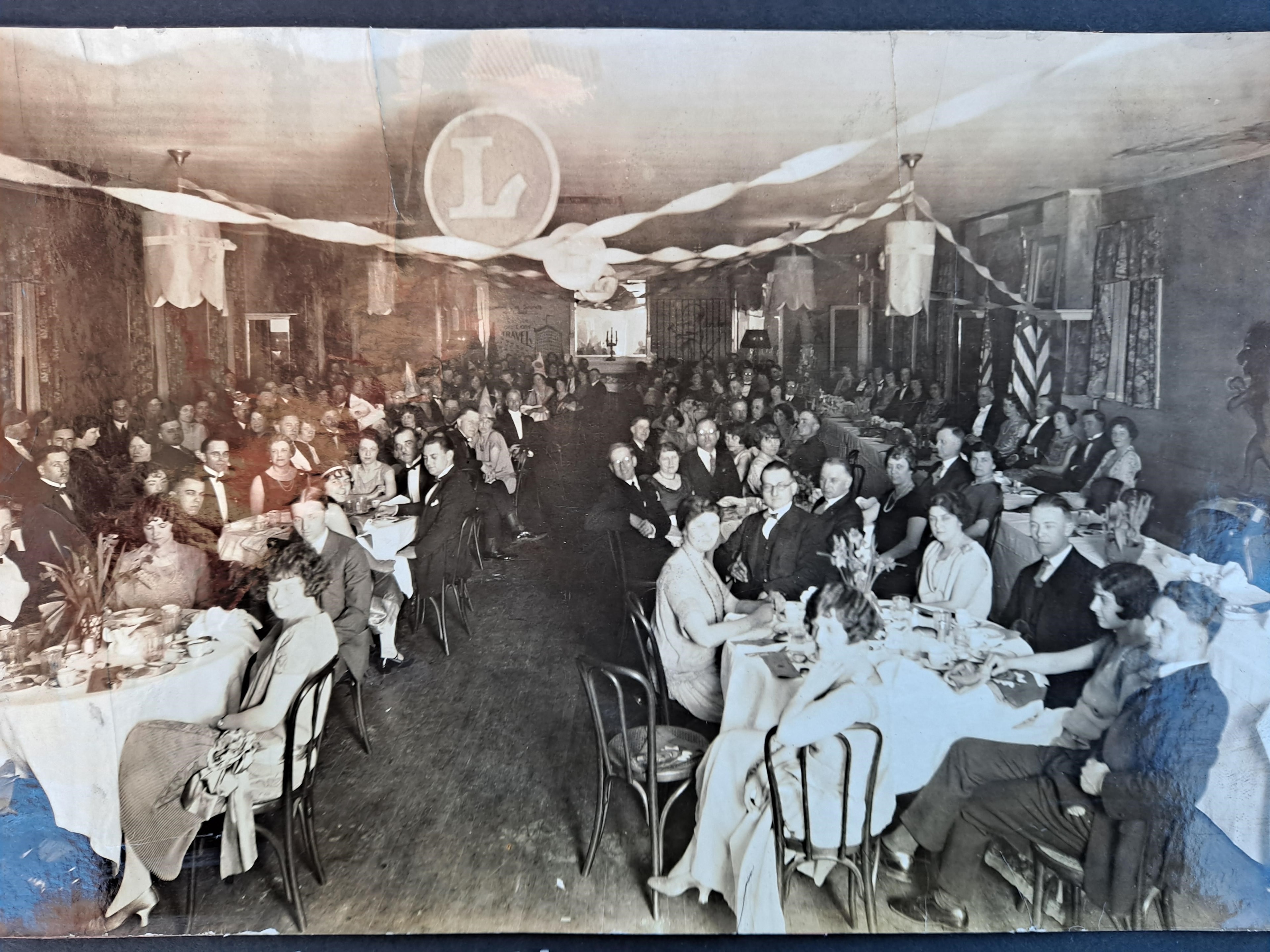 Lancaster Lions Club banquet hall filled with members dining under a Lions "L" emblem banner
